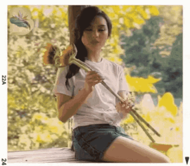 a woman is sitting on a bench holding a sunflower in her hand .