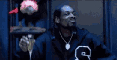 snoop dogg is wearing a fur coat and smoking a cigarette while sitting in a chair .