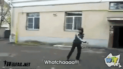 a person standing in front of a building with the words whatchaaa on the bottom right