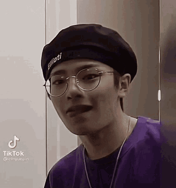 a young man wearing glasses and a beret is making a face .