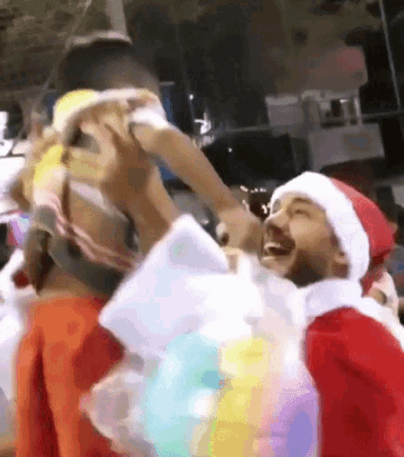 a man in a santa hat is carrying a child on his shoulders .