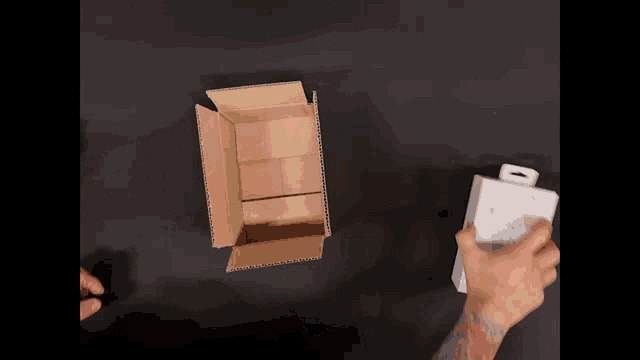 a person is opening a cardboard box on a black surface