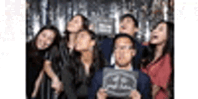 a group of people are standing next to each other in a photo booth .