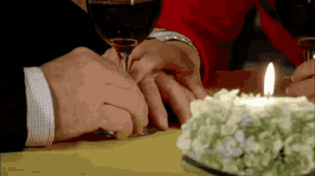a man and woman holding hands at a table with a candle