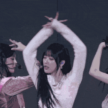 a group of women are dancing on a stage and one of them is wearing a microphone .