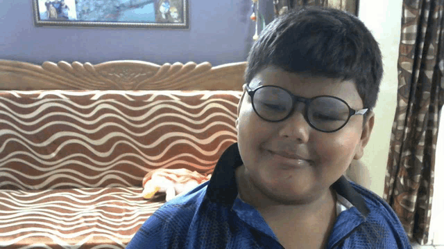 a young boy wearing glasses and a blue shirt smiles for the camera