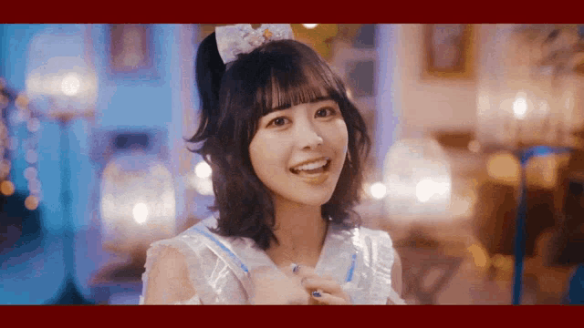 a girl in a white dress with a bow on her head smiles