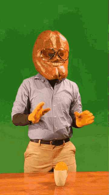 a man with a bread head and glasses stands in front of a cup of orange juice