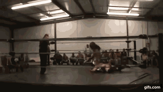 a man is standing in a wrestling ring while a woman is laying on the ground .