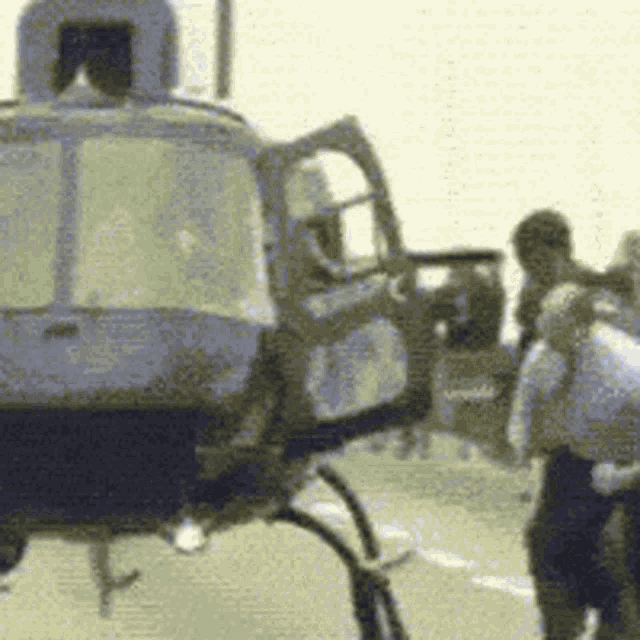 a group of people are standing around a blue helicopter with the door open .