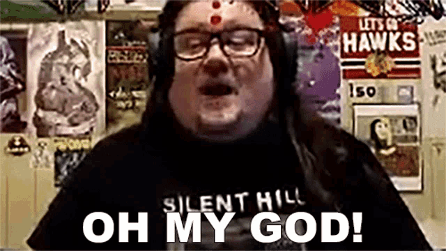 a man wearing headphones and a silent hill shirt is saying `` oh my god '' .