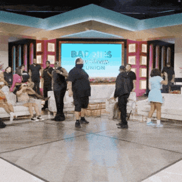 a group of people are gathered in front of a large screen that says baddies american union