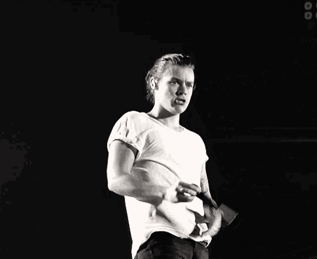 a man in a white shirt holds a microphone in his hand