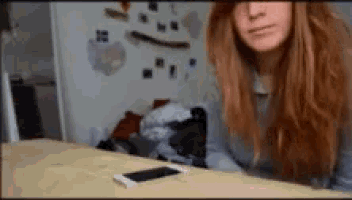 a woman sitting at a table with a cell phone on it