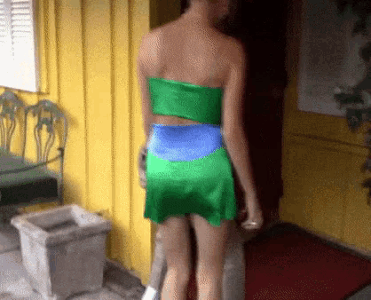 a woman in a green and blue dress is standing in a doorway