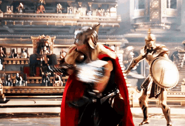 a man in a red cape is standing in front of a statue of a man with a shield
