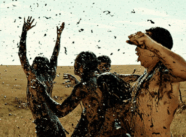 a group of people are covered in mud and birds are flying in the background