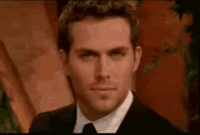 a man in a suit and tie is looking at the camera and smiling .