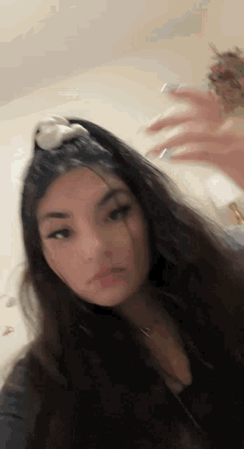 a woman with long hair is taking a selfie with a teddy bear in her hair .