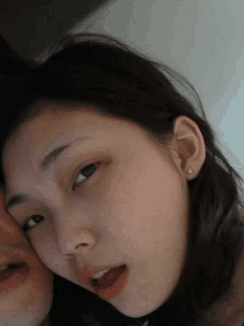 a close up of a woman 's face with a man 's face behind her
