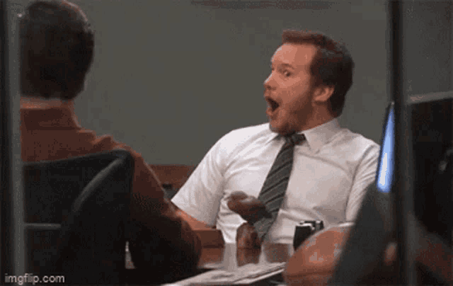 a man is sitting at a desk with his mouth open