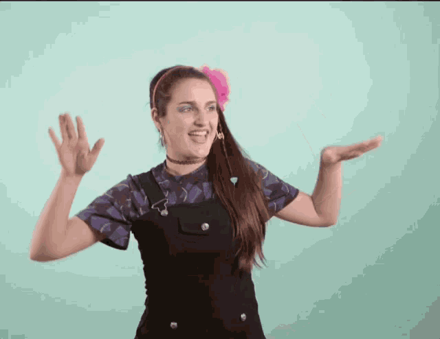 a woman with a pink flower in her hair is dancing with her hands outstretched