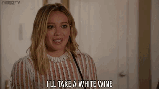 a woman is talking about taking a white wine while wearing a striped shirt .