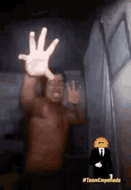 a shirtless man is standing in front of a window with his hand up .