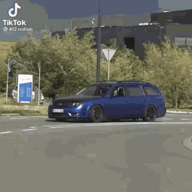 a blue car is driving down a street with the letters tiktok on the bottom
