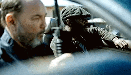 a man is holding a gun while another man is sitting in a car .