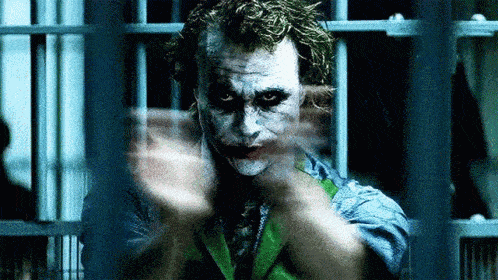 a close up of the joker in a jail cell behind bars .
