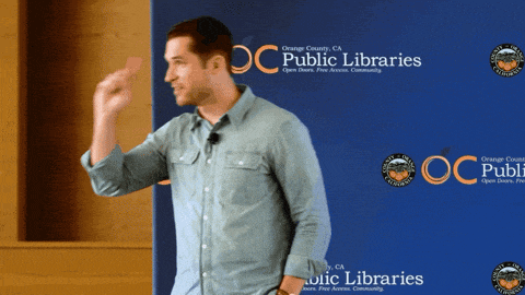 a man giving a speech in front of a blue backdrop that says public libraries
