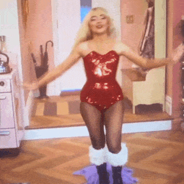 a woman in a red sequined bodysuit is dancing in a kitchen
