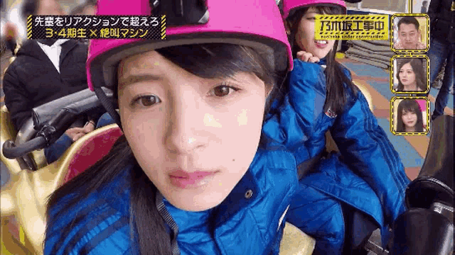 a girl wearing a pink helmet is sitting on a roller coaster