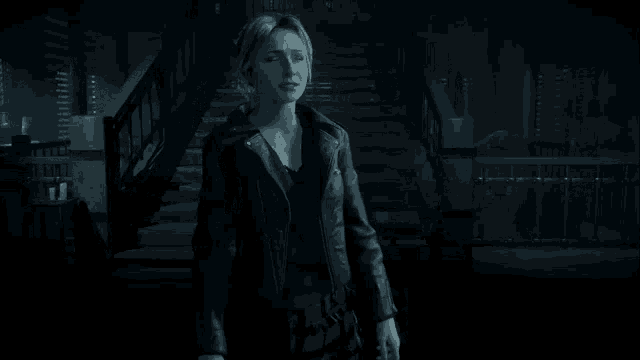 a woman in a black jacket is standing in front of a set of stairs