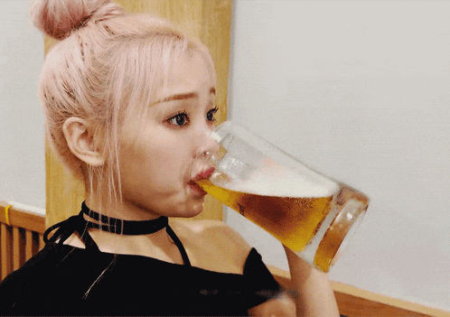 a woman with pink hair is drinking from a large glass
