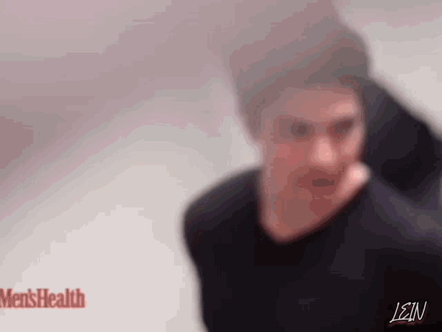 a blurry picture of a man in a black shirt standing in front of a men 's health sign .