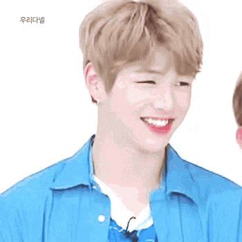 a young man wearing a blue shirt is smiling and winking .