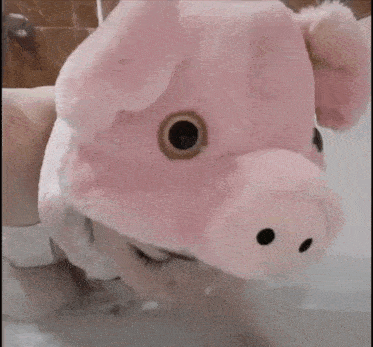 a woman wearing a pig hat is taking a bath in a bathtub .