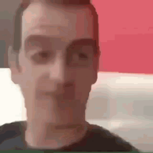 a close up of a man 's face in front of a red and white wall .