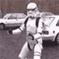 a storm trooper is standing in a parking lot in front of a car .