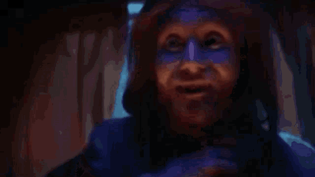 a person with blue paint on their face is talking on a cell phone .