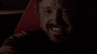 a man with a beard is smiling and making a funny face while sitting in a car .