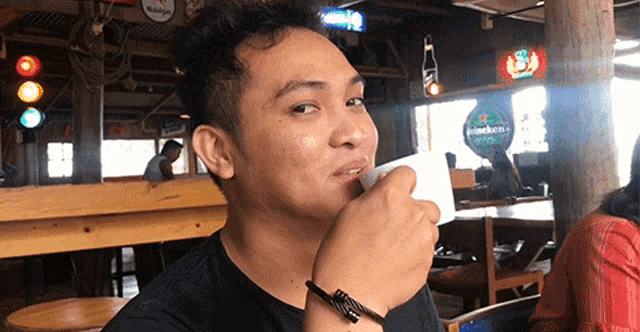 a man is drinking from a white cup in a restaurant .