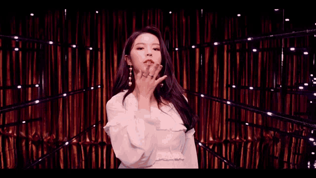 a woman in a white dress is standing in front of a red curtain