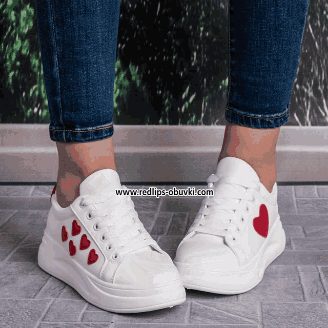 a woman wearing a pair of white shoes with red hearts on the side