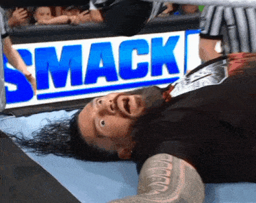 a wrestler is laying on the ground in front of a smack sign