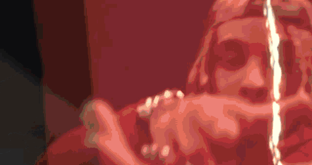 a close up of a person 's face with a red background and a flame coming out of it .