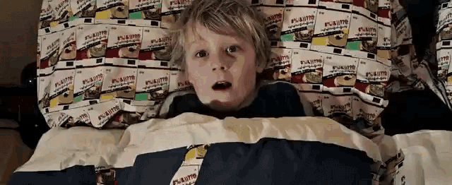 a young boy is laying in bed with a blanket that says peanuts