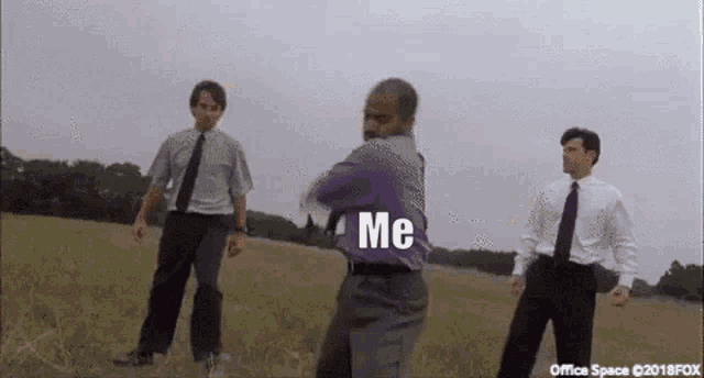 a man in a purple shirt is dancing in a field with two other men in suits and ties .